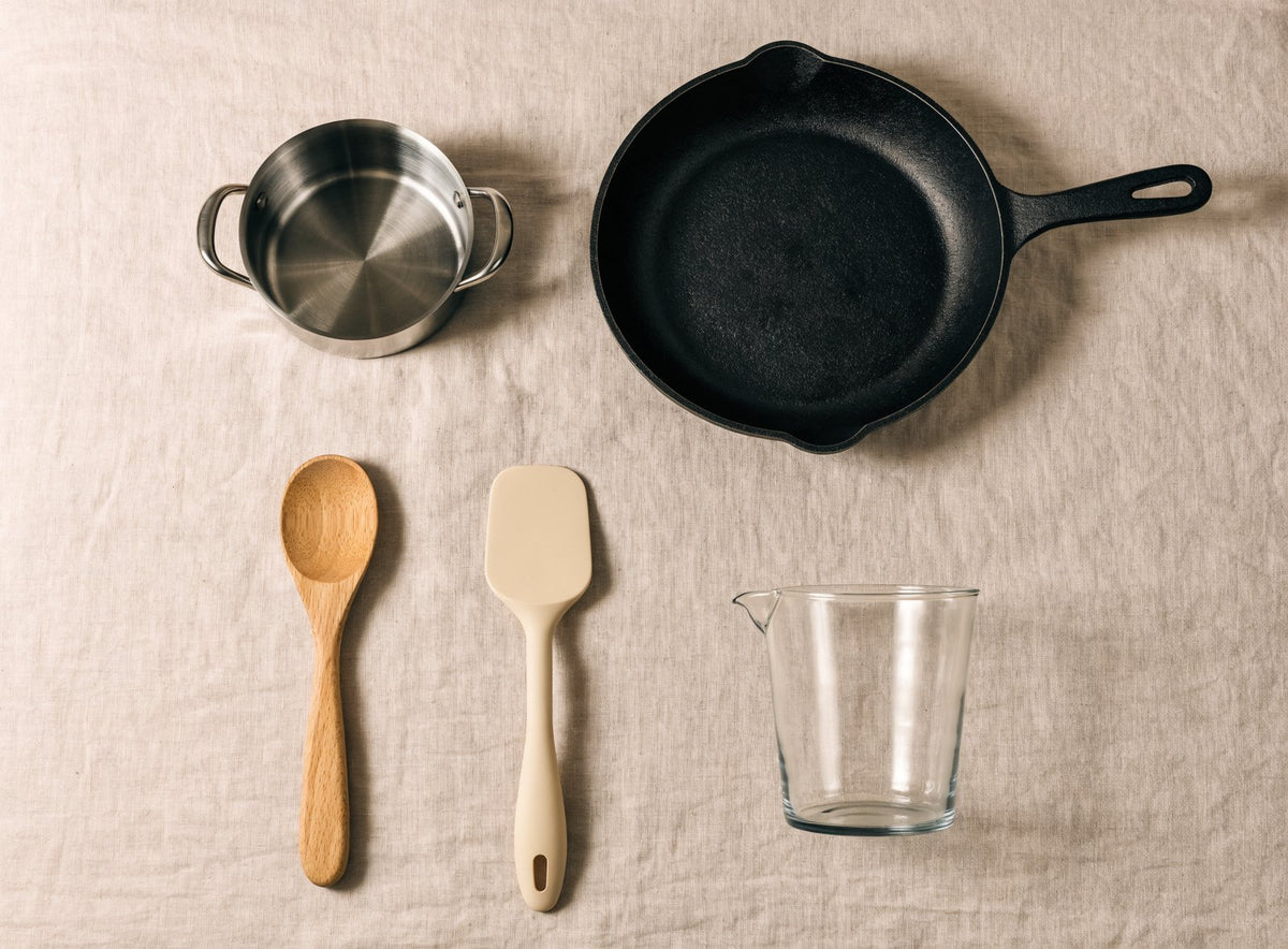 Casserole en inox, poêle en fonte, cuillère en bois, spatule en silicone et verre doseur Image